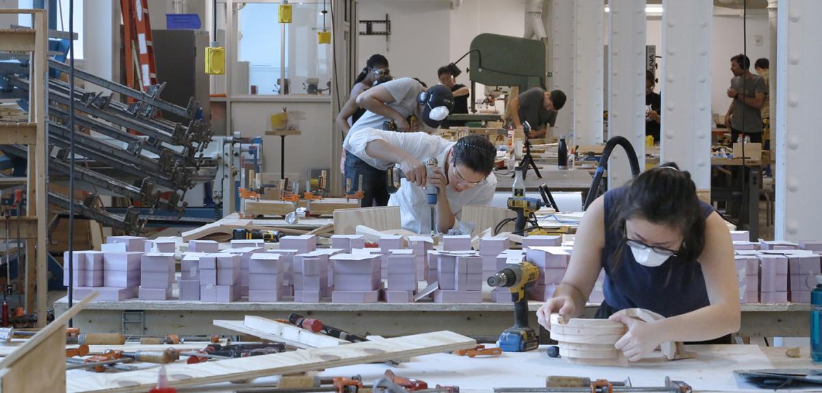 students working with drills and other tools in a large open indoor space