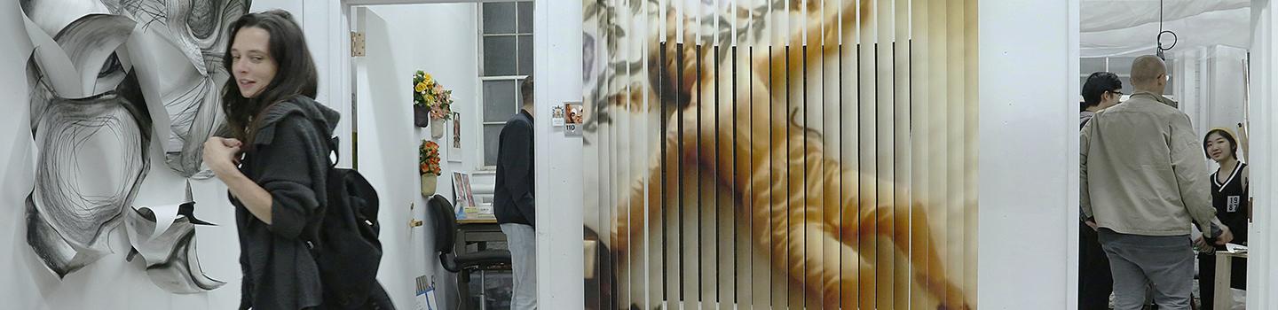 Students interacting in a studio workspace with a sculpture and a painting of a person on the walls