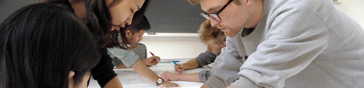 students around on both sides of a table looking at plans