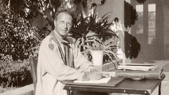 black and white image of a man in an overcoat sitting at a desk outside