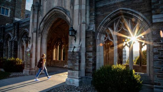 A person walking into an archway with a sunlit lens flair peeking through.