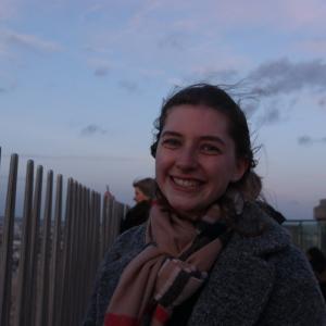 student in scarf along a fence