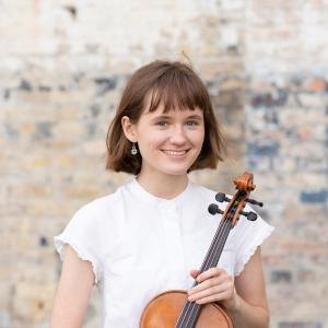 Girl in white shirt holding an instrument 