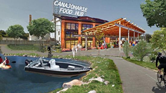 A boat in the water next to a building and sidewalk with people walking around.