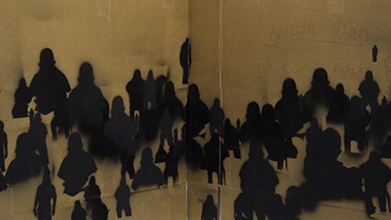 Black spray painted figures on cardboard.