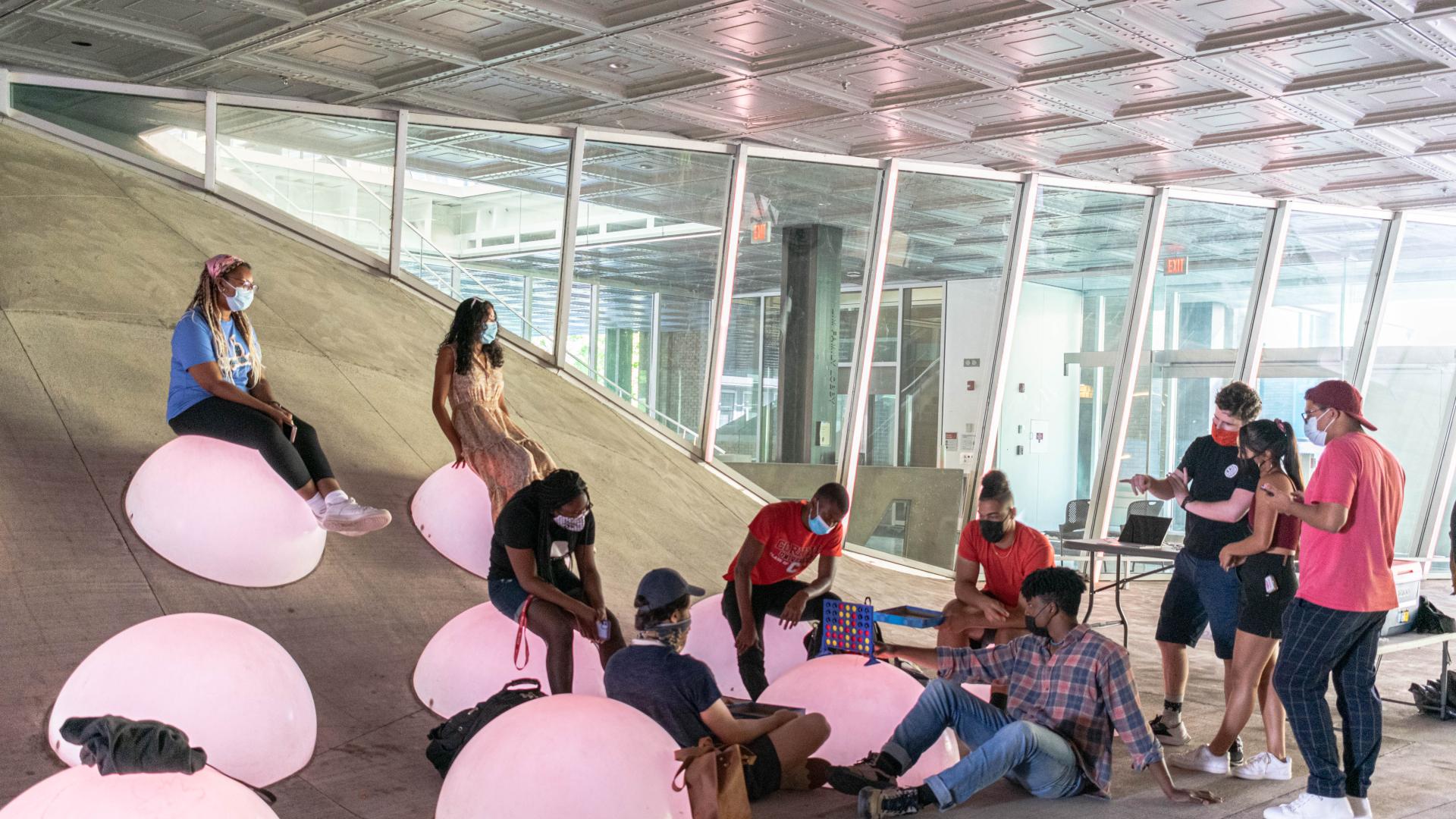 People gathered around sitting on large pink glowing bubbles playing board games.