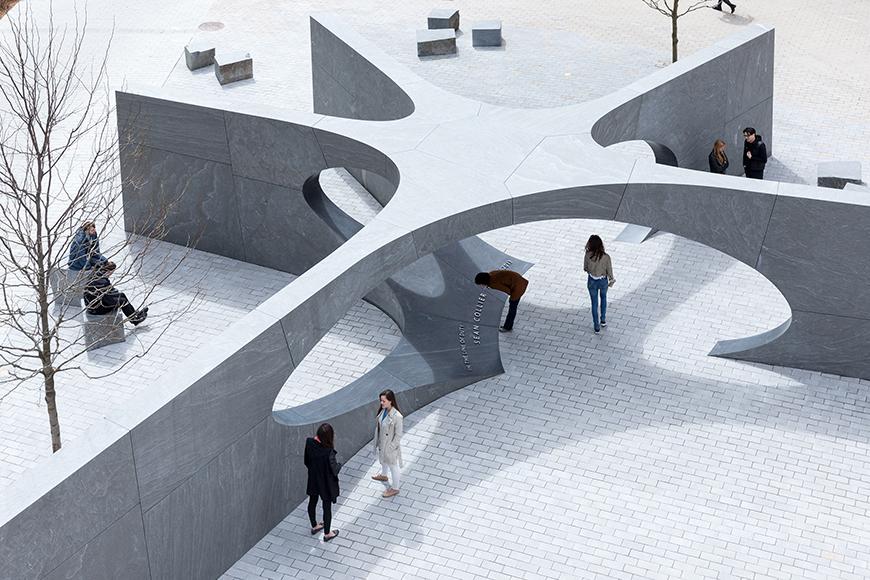five pointed star-shaped sculpture with people walking around and underneath the central arch