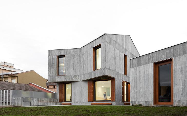 contemporary two story concrete residence with an angled buttress and large windows