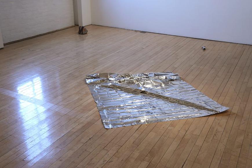 emergency blanket on the floor with two stones nearby, one covered in Lopi wool